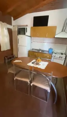a kitchen with a wooden table with chairs and a stove at Lo de Alicia 3 in Villa Carlos Paz