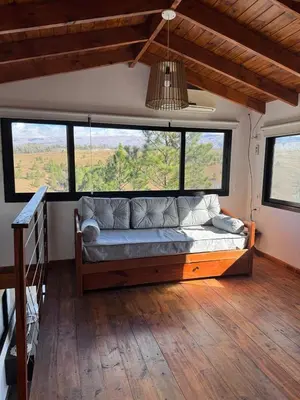 a bedroom with a couch in a room with windows at La Colina de Villa Yacanto in Villa Yacanto