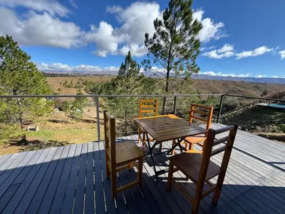 a wooden table and chairs on a deck with a view at La Colina de Villa Yacanto in Villa Yacanto