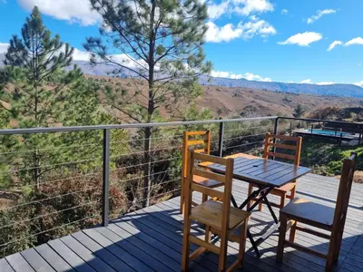 a table and chairs on a deck with a view at La Colina de Villa Yacanto in Villa Yacanto