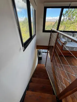 a staircase in a tiny house with a large window at La Colina de Villa Yacanto in Villa Yacanto