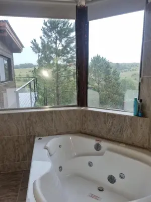 a bath tub in a bathroom with a large window at La Colina de Villa Yacanto in Villa Yacanto