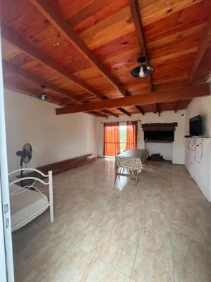 a large living room with wooden ceilings and a fireplace at cabaña con pileta in Villa Anizacate