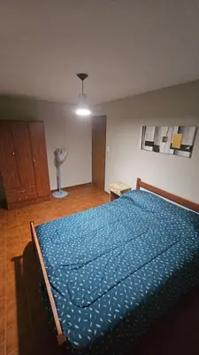 a bedroom with a bed with a blue comforter at Arenas Departamentos in Mina Clavero