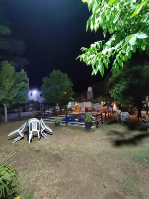 a group of lawn chairs and a pool at night at Arenas Departamentos in Mina Clavero