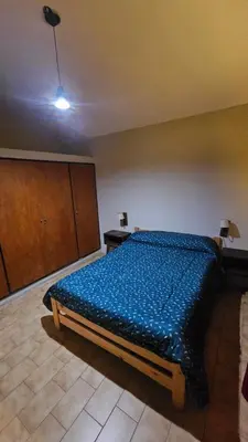 a bedroom with a bed with a blue comforter at Arenas Departamentos in Mina Clavero