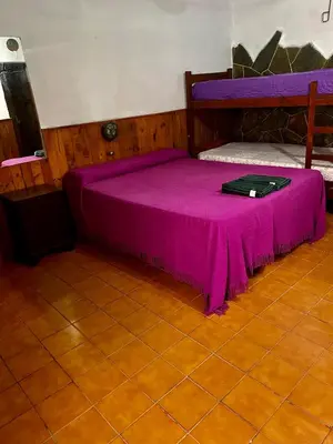 a purple bed in a room with a table at Hosteria Rosales in Trapiche