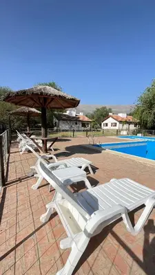 a row of lounge chairs and an umbrella next to a pool at Cabañas Aldea Blanca in Merlo