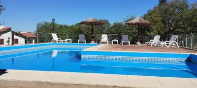 a swimming pool with chairs and umbrellas at Cabañas Aldea Blanca in Merlo