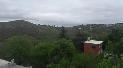 a small red building in the middle of a mountain at Departamento en Villa del Lago, Carlos Paz in Villa Carlos Paz