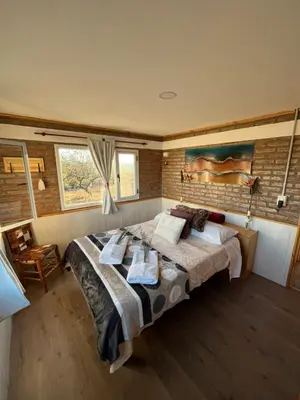 a bedroom with a large bed and a brick wall at Terraza de Amancay in Villa Amancay