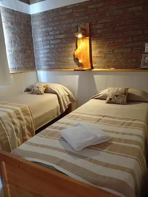 two beds in a room with a brick wall at Terraza de Amancay in Villa Amancay
