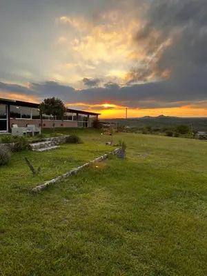 a building on a field with a sunset in the background at Terraza de Amancay in Villa Amancay