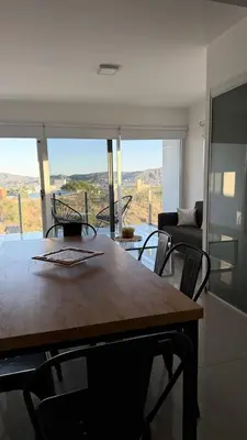 a table and chairs in a living room with a view at Departamento Carilo Carlos Paz in Villa Carlos Paz