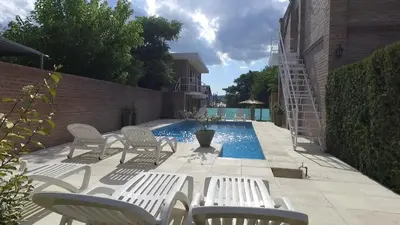 a patio with white chairs and a swimming pool at Hotel Dormi's Solo Adultos in Mina Clavero