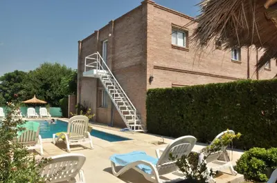 a swimming pool with white chairs and a staircase next to a building at Hotel Dormi's Solo Adultos in Mina Clavero