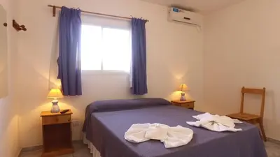 a bedroom with a bed with blue sheets and a window at Hotel Dormi's Solo Adultos in Mina Clavero