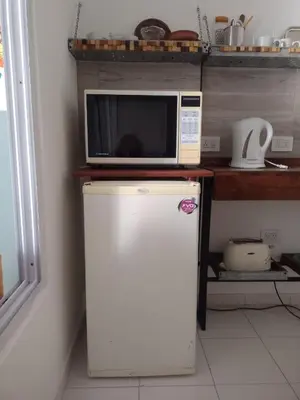 a microwave on top of a refrigerator in a kitchen at Estudio en Nueva Córdoba in Cordoba