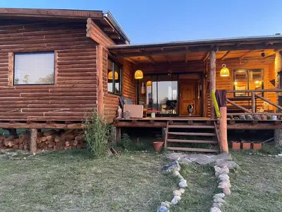 a log cabin with a staircase leading to the front door at Cabaña frente al lago in La Estancia