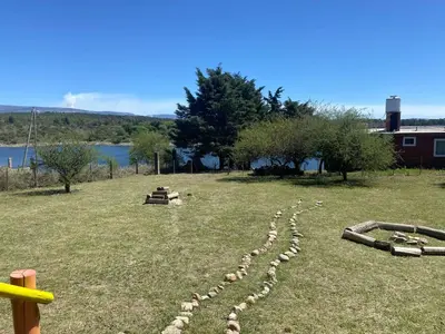 a herd of sheep laying in the grass at Cabaña frente al lago in La Estancia