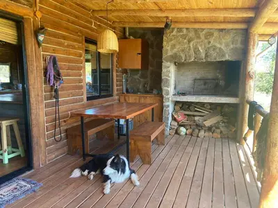 a dog laying on the porch of a cabin with a fireplace at Cabaña frente al lago in La Estancia