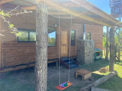 a log cabin with a porch and a swing at Cabaña frente al lago in La Estancia