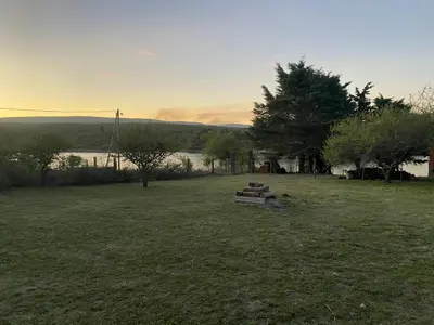 a park with a bench in the middle of a field at Cabaña frente al lago in La Estancia