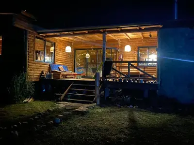 a log cabin with a porch at night at Cabaña frente al lago in La Estancia