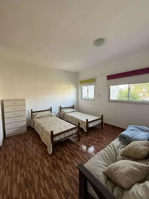 a room with three beds and a window at Depto Santa Cruz in Villa Santa Cruz del Lago