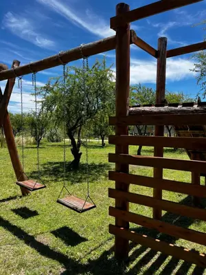 two swings in a field next to a fence at Cabañas La Chakana in Cortaderas