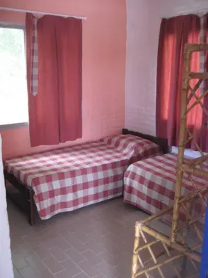 a bedroom with a bed with red curtains and a ladder at casa 8 personas in Mina Clavero