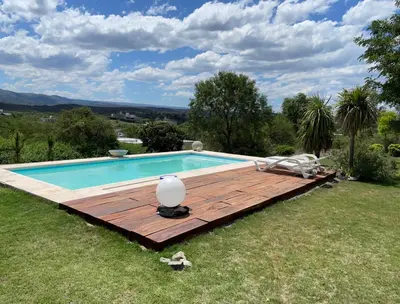 a swimming pool with a wooden deck next to a yard at CASA DE CATEGORIA EN LAS SIERRAS de CORDOBA in San Antonio de Arredondo