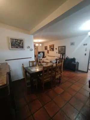 a dining room and living room with a table and chairs at Casa Costa Lago in Villa Carlos Paz