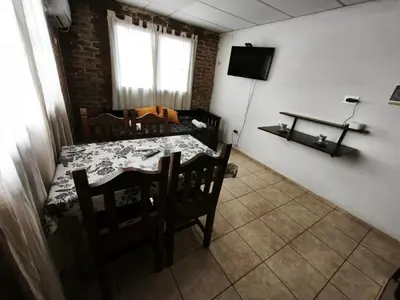 a dining room with a table and chairs and a television at Departamento Villa Cabrera in Cordoba