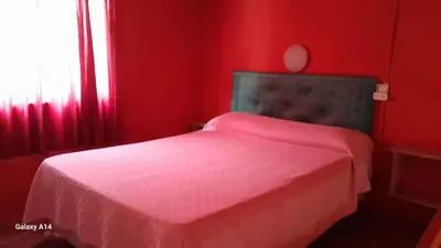 a red bedroom with a bed with a white sheet at Don Pinelli dptos in Alpa Corral