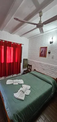 a bedroom with a green bed with red curtains at Hotel Francesco in Mina Clavero