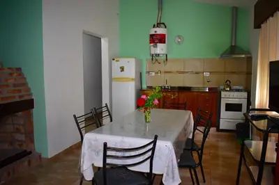 a kitchen with a table with chairs and a refrigerator at Sierras Del Molle in Santa Rosa de Calamuchita