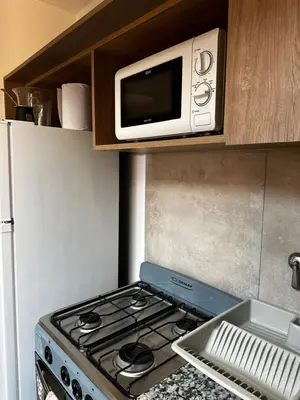 a microwave above a stove in a kitchen at NUEVO a 3 cuadras del shopping Patio Olmos con ASADOR y terraza amoblada in Cordoba
