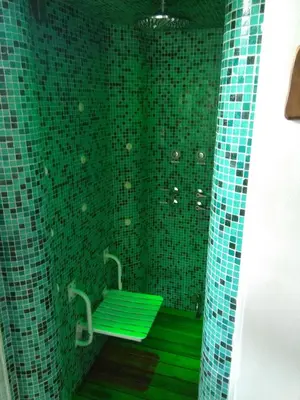 a green tiled bathroom with a green bench at Bad-wiessee Apart Hotel & Spa in Villa General Belgrano