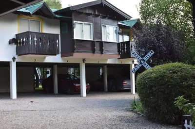 a house with a balcony with cars parked in it at Bad-wiessee Apart Hotel & Spa in Villa General Belgrano