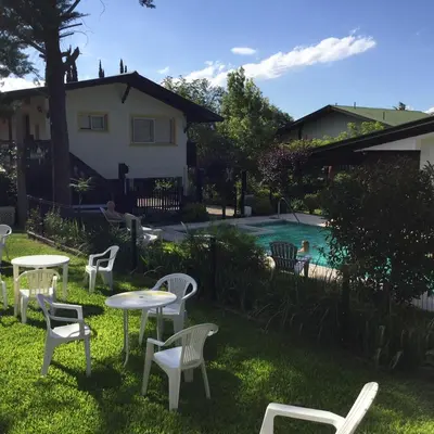 a yard with white tables and chairs and a pool at Bad-wiessee Apart Hotel & Spa in Villa General Belgrano