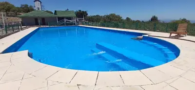 a large blue swimming pool with a bench around it at El Paraíso de las Chacras in Las Chacras (La Paz)