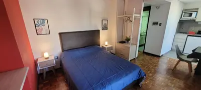 a bedroom with a blue bed and a kitchen at Departamento Plaza San Martín in Cordoba