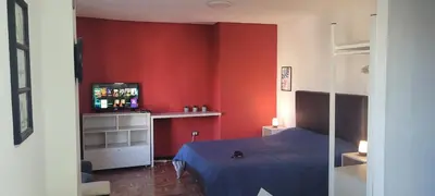 a bedroom with red walls and a bed and a television at Departamento Plaza San Martín in Cordoba