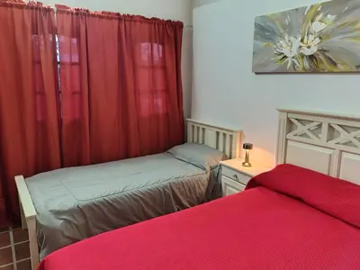 two beds in a room with red curtains at La Carolina Cabañas in Almafuerte