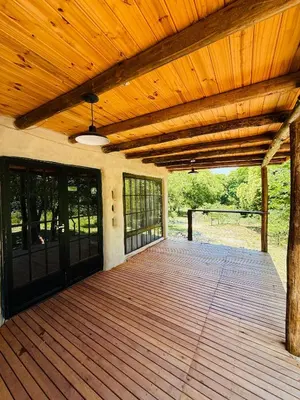 a wooden porch with a wooden ceiling and a wooden deck at Tierra de Arroyo, Mallin-Tanti in Tanti