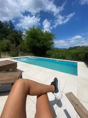 a woman sitting on a bench next to a swimming pool at La curva del molino in Villa Parque Siquiman