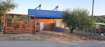 a house with a blue roof and a wooden gate at La curva del molino in Villa Parque Siquiman