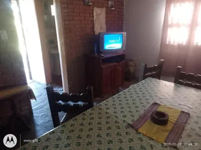 a dining room with a table and a television at CASA ANTONIO-sobre el rio in Villa Carlos Paz