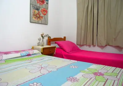 two beds in a room with pink sheets at Apartamento del Sol para 5 in Villa Carlos Paz